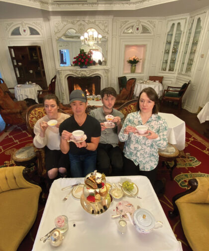 Four people pose holding teacups.
