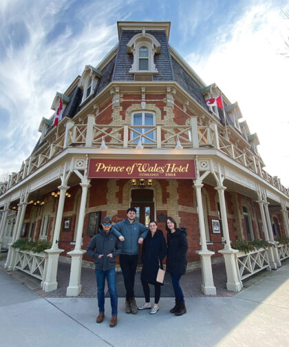 Four people post in front of the Prince of Wales Hotel.