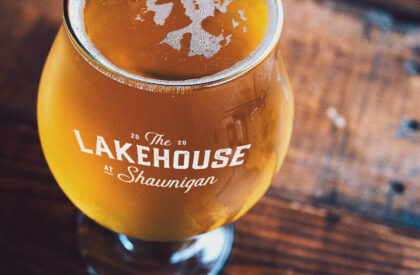 A photo of a glass of beer. The glass is branded with The Lakehouse at Shawnigan.